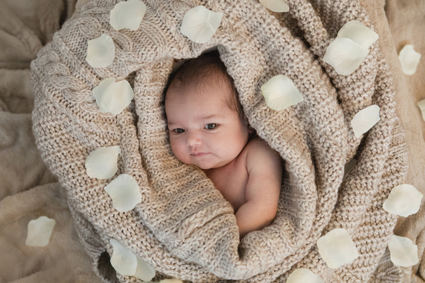 bebe rodeado de manta y petalos de Momem Fotografia