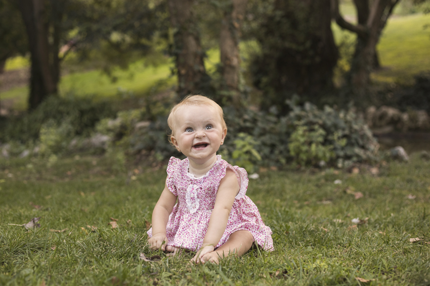 niña sobre cesped sonriendo de Momem Fotografia