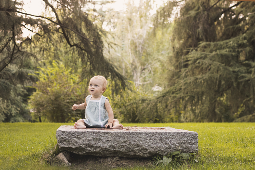 Bebe sentada en piedra en jardin de Momem Fotografia